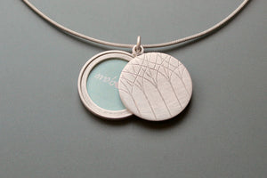 minimalistic silver locket for a picture with forest design
