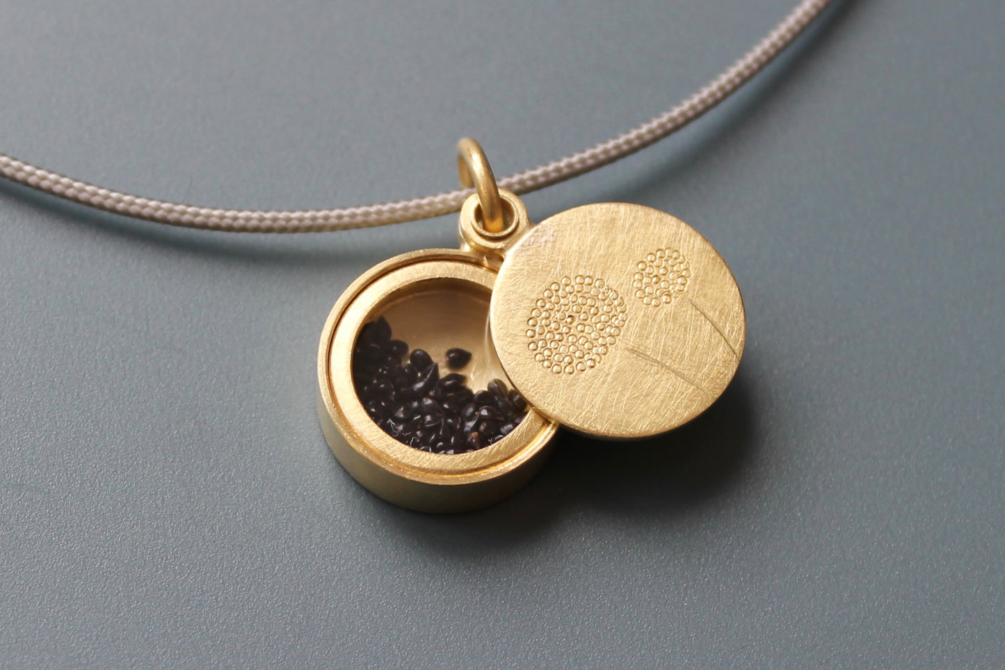 golden dandelion locket filled with forget me not seeds