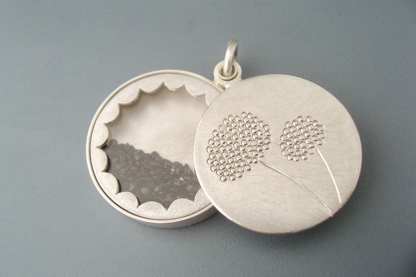 elegant floating locket filled with forget-me-not-seeds in sterling silver with dandelions design
