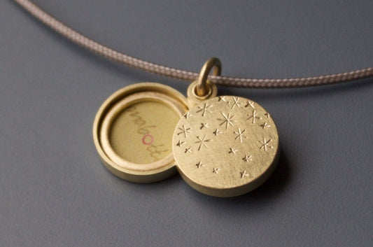 round gold locket for two photos with many stars on the lid