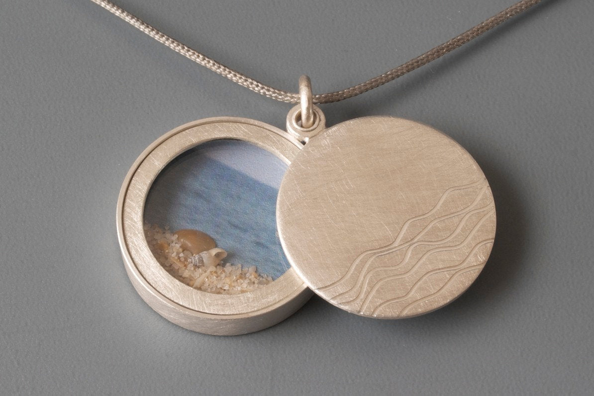 silver floating glass locket filled with seashells with waves design