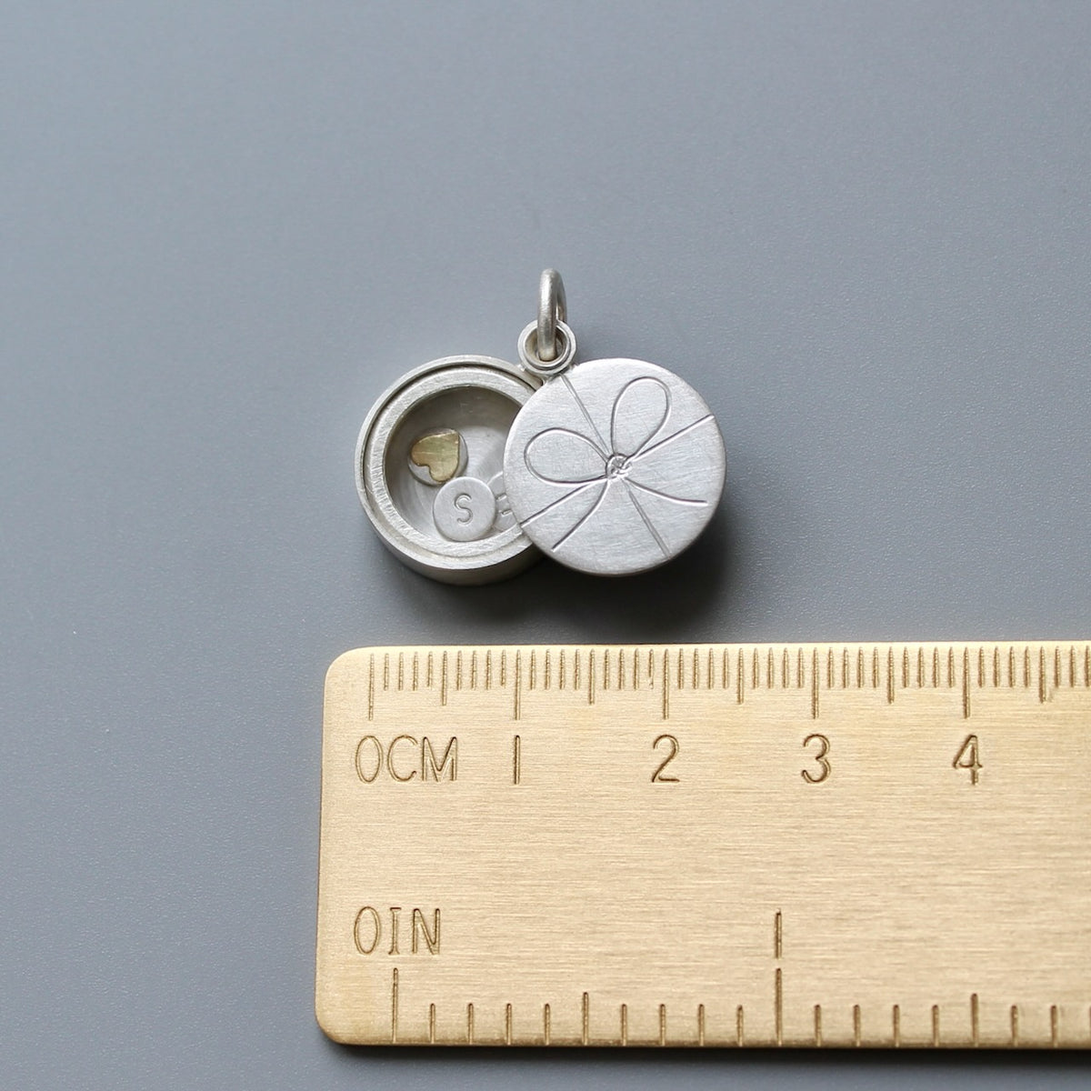 sterling silver gift locket with bow knot filled with custom initials and heart