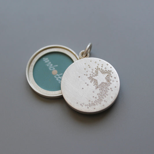 Silver mabotte locket with a shooting star design on the outside