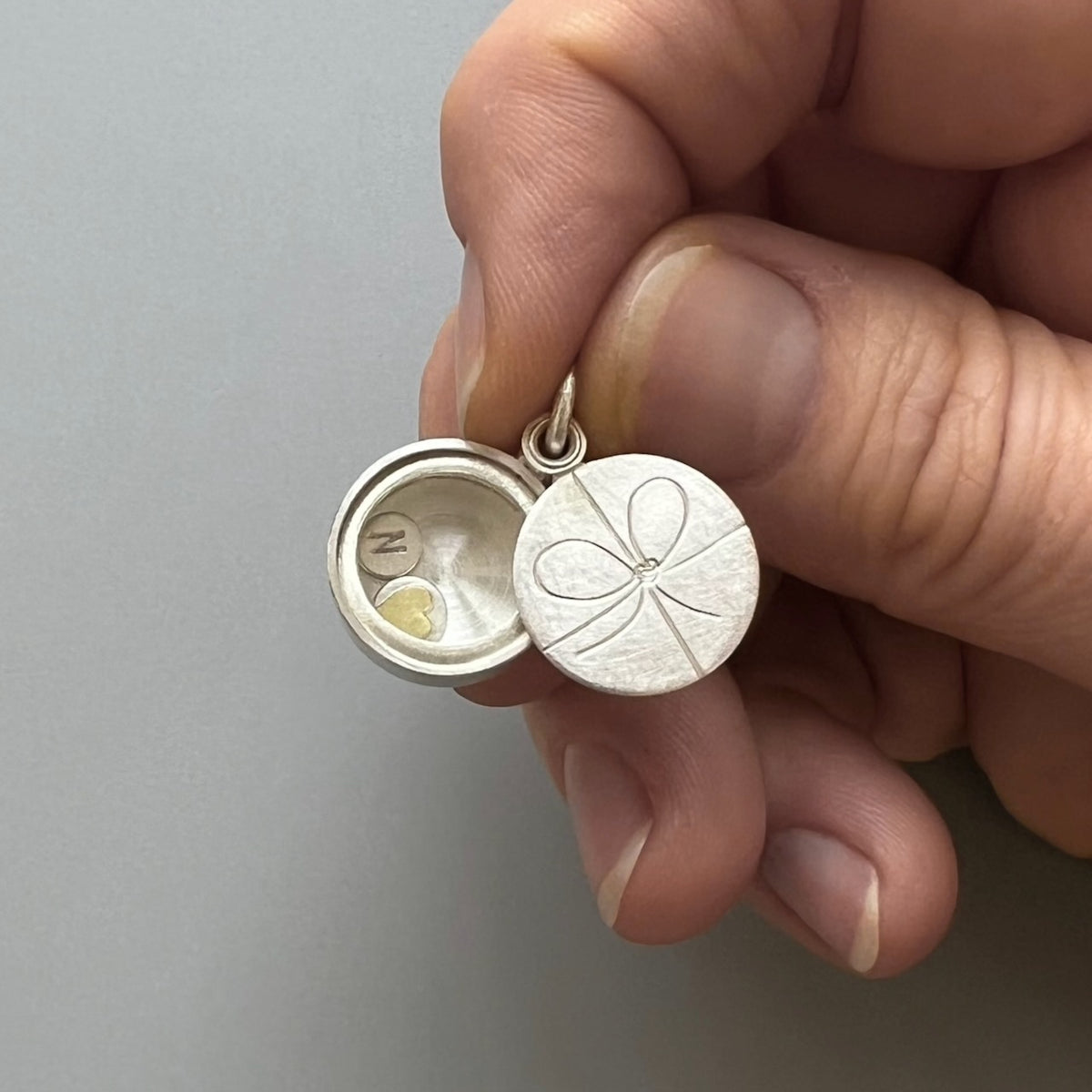 sterling silver gift locket with bow knot filled with custom initials and heart