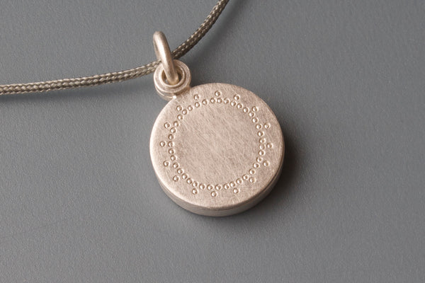small silver locket with delicate lace patter