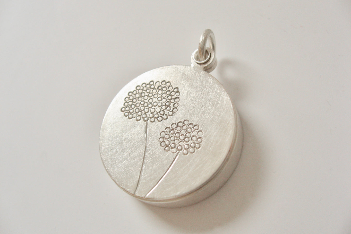 elegant floating locket filled with forget-me-not-seeds in sterling silver with dandelions design