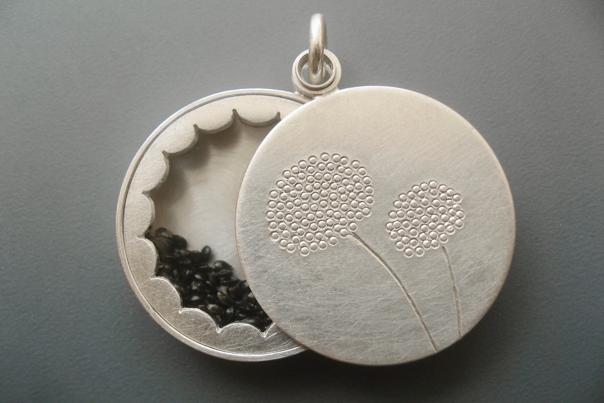 elegant floating locket filled with forget-me-not-seeds in sterling silver with dandelions design