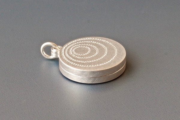 silver double sided photo locket with concentric circles